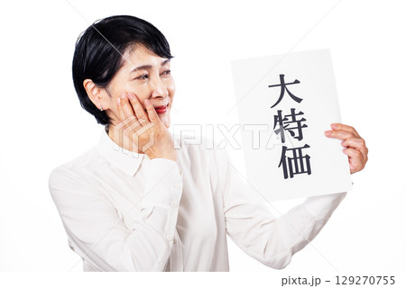 大特価と書かれた紙を持ち頬杖をつきながら微笑む中年女性 大特価と書かれた紙を持ち頬杖をつきながら微笑む中年女性 129270755