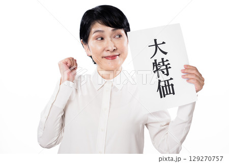 大特価と書かれた紙を持ち嬉しそうに目線を送る白いシャツを着た中年女性 大特価と書かれた紙を持ち嬉しそうに目線を送る白いシャツを着た中年女性 129270757