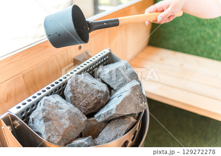 サウナでロウリュする女性の手元 129272278