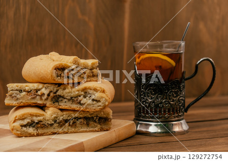 freshly baked meat pie with tea served on rustic wooden table. closeup. 129272754