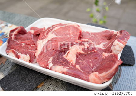 Fresh raw beef steaks on white tray outdoor setting Fresh raw beef steaks on white tray outdoor setting 129273700
