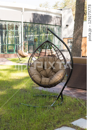 Cozy outdoor hanging chair on a sunny day in relaxing garden setting 129273778
