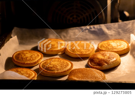Golden mini pancakes baking on parchment paper inside a warm oven, symbolizing delightful homemade comfort food and sweet culinary creations Golden mini pancakes baking on parchment paper inside a warm oven, symbolizing delightful homemade comfort food and sweet culinary creations 129273805