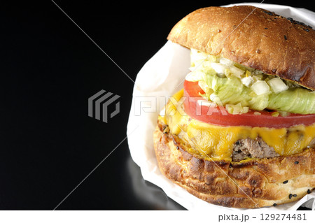 袋に包まれているチェダーチーズたっぷりのハンバーガーを黒背景で撮影 袋に包まれているチェダーチーズたっぷりのハンバーガーを黒背景で撮影 129274481