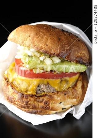 袋に包まれているチェダーチーズたっぷりのハンバーガーを黒背景で撮影 袋に包まれているチェダーチーズたっぷりのハンバーガーを黒背景で撮影 129274488