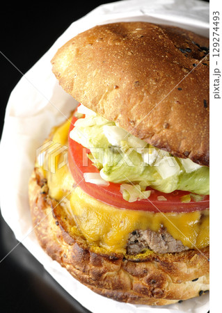 袋に包まれているチェダーチーズたっぷりのハンバーガーを黒背景で撮影 袋に包まれているチェダーチーズたっぷりのハンバーガーを黒背景で撮影 129274493