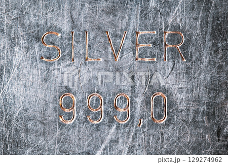 Silver bar stamp impression. Old silver bullion, tarnished and scratched by storage and handling, in which the word SILVER was stamped, as well as 999.0 purity, which means 99.9 percent pure silver. 129274962