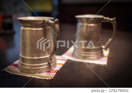 Pair of vintage Japanese beer mugs placed on patterned textile coasters 129276002