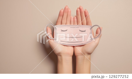 Air quality and pollution concept with face mask protection, Hands holding a drawn smiley face mask against a neutral background. 129277252