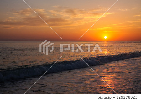 beautiful and colorful sunset, warm light and many clouds, sea waves on the sea coast 129278023