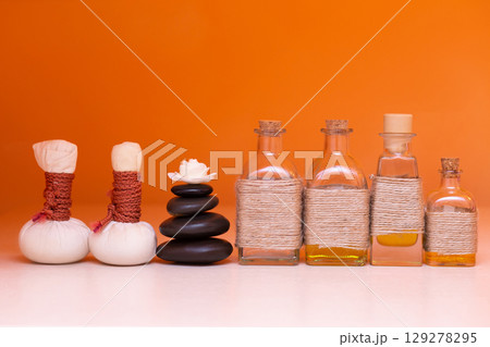 beautiful bottles with massage oil on orange background 129278295