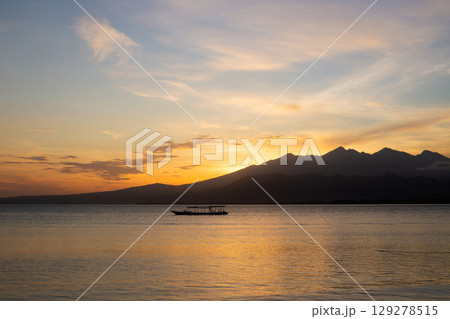beautiful dramatic landscape of sunset on sea beach with silhouette of boat 129278515