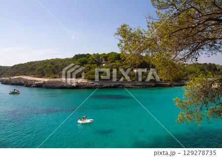 people are sailing on an inflatable boat in a beautiful clear sea 129278735