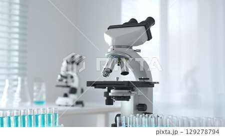 Modern microscopes and test tubes containing blue liquid are arranged on a table in a bright laboratory setting, ready for scientific research and analysis Modern microscopes and test tubes containing blue liquid are arranged on a table in a bright laboratory setting, ready for scientific research and analysis 129278794