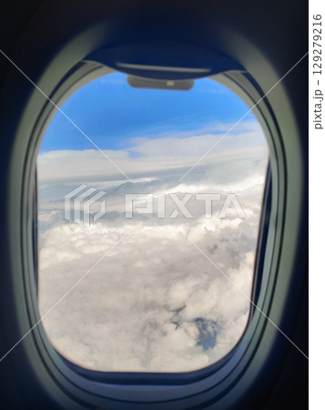 beautiful thick clouds in the sky from the height of the flight of the plane with a view of the wing with engines through the round window beautiful thick clouds in the sky from the height of the flight of the plane with a view of the wing with engines through the round window 129279216