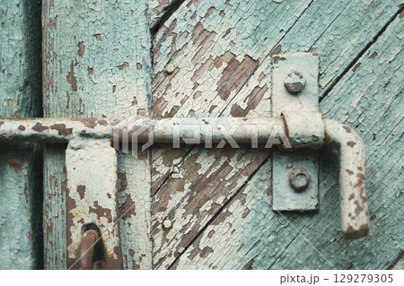 old metal lock on a wooden door with cracked paint 129279305