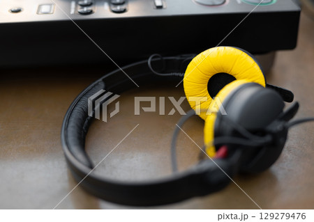 stylish yellow DJ headphones near the controller on the table stylish yellow DJ headphones near the controller on the table 129279476
