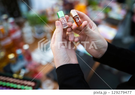 holding small glass jars with different scents in their hands 129279477