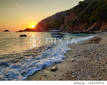 beautiful dramatic landscape of sunset on sea beach with silhouette of boat 129279752