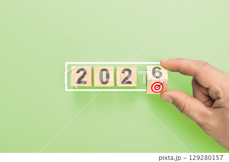 Hand completing 2026 new year business goals. Man putting last wooden block with target icon in white frame concept Hand completing 2026 new year business goals. Man putting last wooden block with target icon in white frame concept 129280157