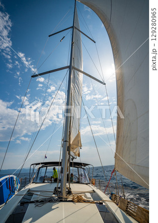 White sails filled with wind, seen from the bow of a sailing yacht near Croatia. Freedom, clean energy, adventure and mindful travel on the open sea. 129280965