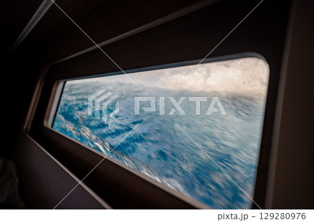 View through the bow cabin window of a sailing yacht leaning into the sea near Croatia. Sailing in strong wind, heeling movement and immersive life on board. 129280976