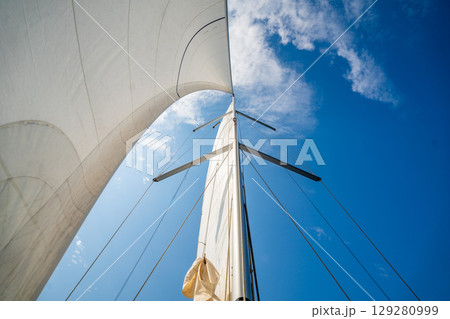 White sails filled with wind, seen from the bow of a sailing yacht near Croatia. Freedom, clean energy, adventure and mindful travel on the open sea. White sails filled with wind, seen from the bow of a sailing yacht near Croatia. Freedom, clean energy, adventure and mindful travel on the open sea. 129280999