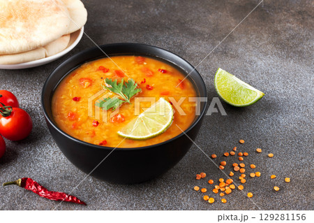 Red lentil soup with spices and fresh herbs on a gray background. Indian dal soup. Indian Food. Red lentil soup with spices and fresh herbs on a gray background. Indian dal soup. Indian Food. 129281156