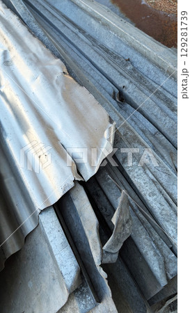 Piles of weathered metal sheets and strips, showcasing various textures and colors, stacked in a disorganized manner, reflecting industrial materials and construction elements 129281739