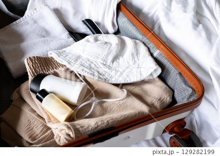 Open suitcase with travel essentials. Hat, clothing, and toiletries for a vacation 129282199