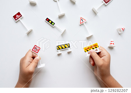 Child hands holding toy road signs on white background 129282207