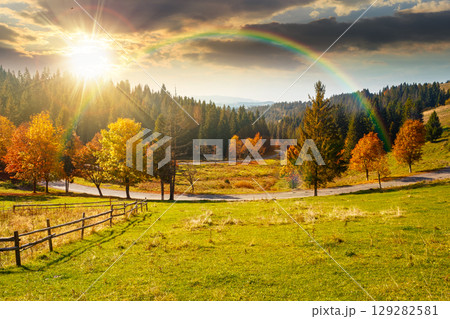 countryside mountain landscape in autumn at sunset. rural road winding through valley among field and trees on the hill. scenic vista in fall season for travel and outdoor adventure in evening light 129282581