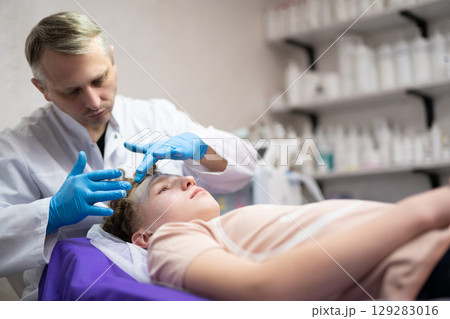 a cosmetologist doctor makes cosmetic procedures on the face of a young guy in a beauty salon 129283016