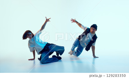 Two hip hop dancers balancing on hands with expressive open-arm gestures and urban styling 129283350