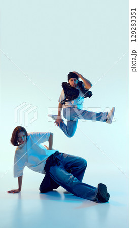 Street dancer mid-air with intense expression while partner supports pose on floor Street dancer mid-air with intense expression while partner supports pose on floor 129283351