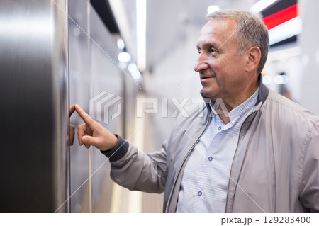 Elderly passenger reads train schedule at metro station Elderly passenger reads train schedule at metro station 129283400