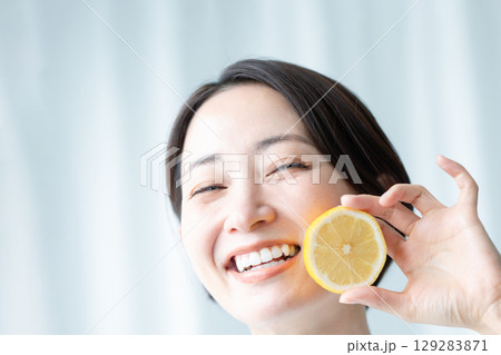 レモンを手に持ってフレッシュな笑顔を見せる透明感のある女性 顔のアップ 129283871