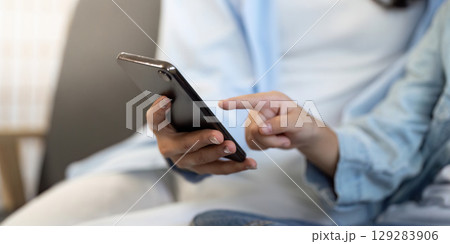 Digital Connection. Person interacting with smartphone in a cozy indoor setting. 129283906