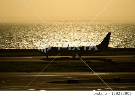 夕焼けのセントレアと飛行機のある風景 129283909
