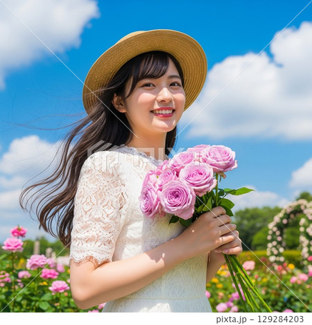 薔薇の花束を持ち麦わら帽子を被り笑顔を見せる女性のバストショット 薔薇の花束を持ち麦わら帽子を被り笑顔を見せる女性のバストショット 129284203