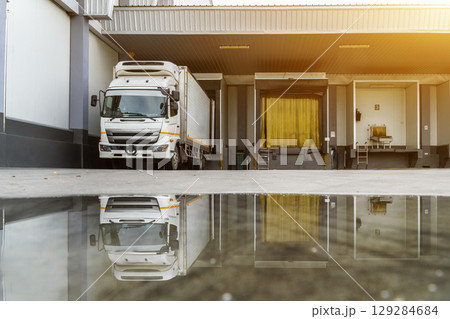 Trailer Container Truck Parked in front of the ramps for load/unload goods at the distribution warehouse center in the factory. Shipping Shipment Cargo concept. Trailer Container Truck Parked in front of the ramps for load/unload goods at the distribution warehouse center in the factory. Shipping Shipment Cargo concept. 129284684