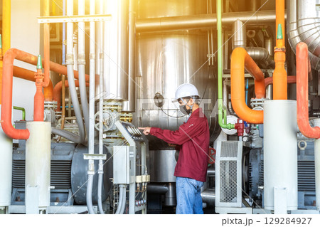 Young man mechanical engineer is checking and inspection of HVAC heating ventilation air conditioning system and pipping line of industrial construction at boiler pump room system. 129284927