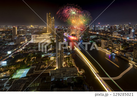 Modern buildings in the city with water reflection, firework, light show at night time. 129285021