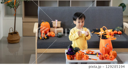 Creative Halloween Fun. A young boy enjoys crafting with festive decorations around him. 129285194