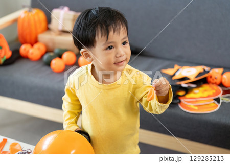Halloween Joy. Toddler smiling while playing with festive decorations. 129285213
