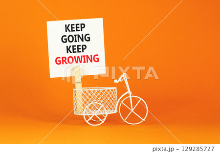 Keep going and growing symbol. Concept words phrase Keep going keep growing on beautiful white paper on clothespin. Beautiful orange paper background. Business Keep going growing concept. Copy space. 129285727