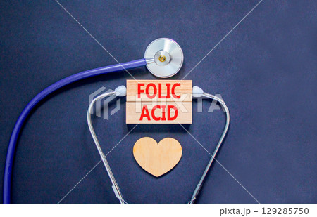 Folic acid symbol. Concept words Folic acid on beautiful wooden blocks. Wooden heart and stethoscope. Beautiful black background. Medical healthy lifestyle folic acid concept. 129285750
