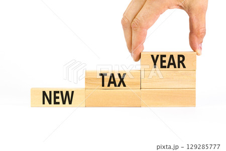 New tax year symbol. Concept words New tax year on beautiful wooden blocks. Beautiful white table white background. Businessman hand. Business new tax year concept. Copy space. New tax year symbol. Concept words New tax year on beautiful wooden blocks. Beautiful white table white background. Businessman hand. Business new tax year concept. Copy space. 129285777