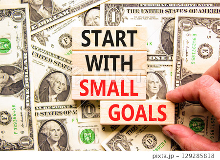 Start with small goals symbol. Concept words phrase Start with small goals on beautiful blocks. Dollar bills. Beautiful dollar bills background. Business Start with small goals concept. Copy space Start with small goals symbol. Concept words phrase Start with small goals on beautiful blocks. Dollar bills. Beautiful dollar bills background. Business Start with small goals concept. Copy space 129285818