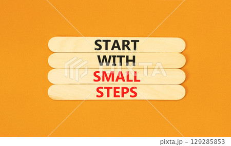 Start with small steps symbol. Concept words phrase Start with small steps on beautiful wooden stick. Beautiful orange paper background. Business Start with small steps concept. Copy space. 129285853